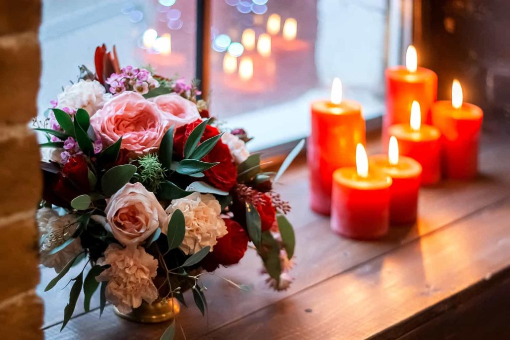 red green candles and bouquet of flowers on a wind